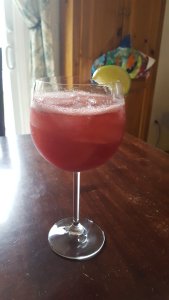 wine glass with pink cocktail and lime garnish